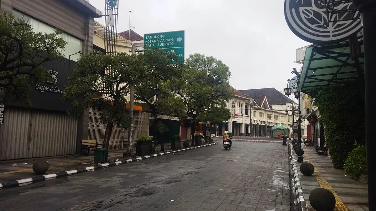Jalan Braga Bandung pada pagi hari dengan trotoar basah, deretan ruko kolonial, dan papan nama kafe