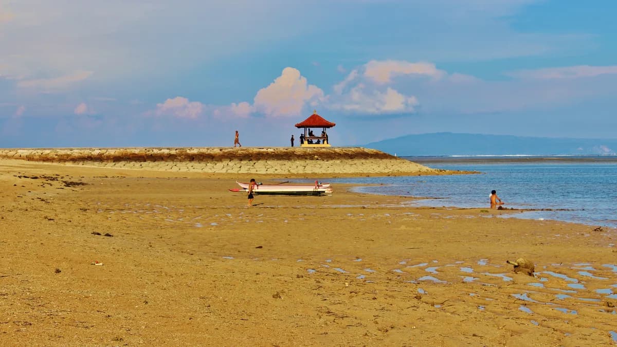 Air dangkal dan tenang di Pantai Sanur dengan bale beratap merah di ujung daratan berpasir