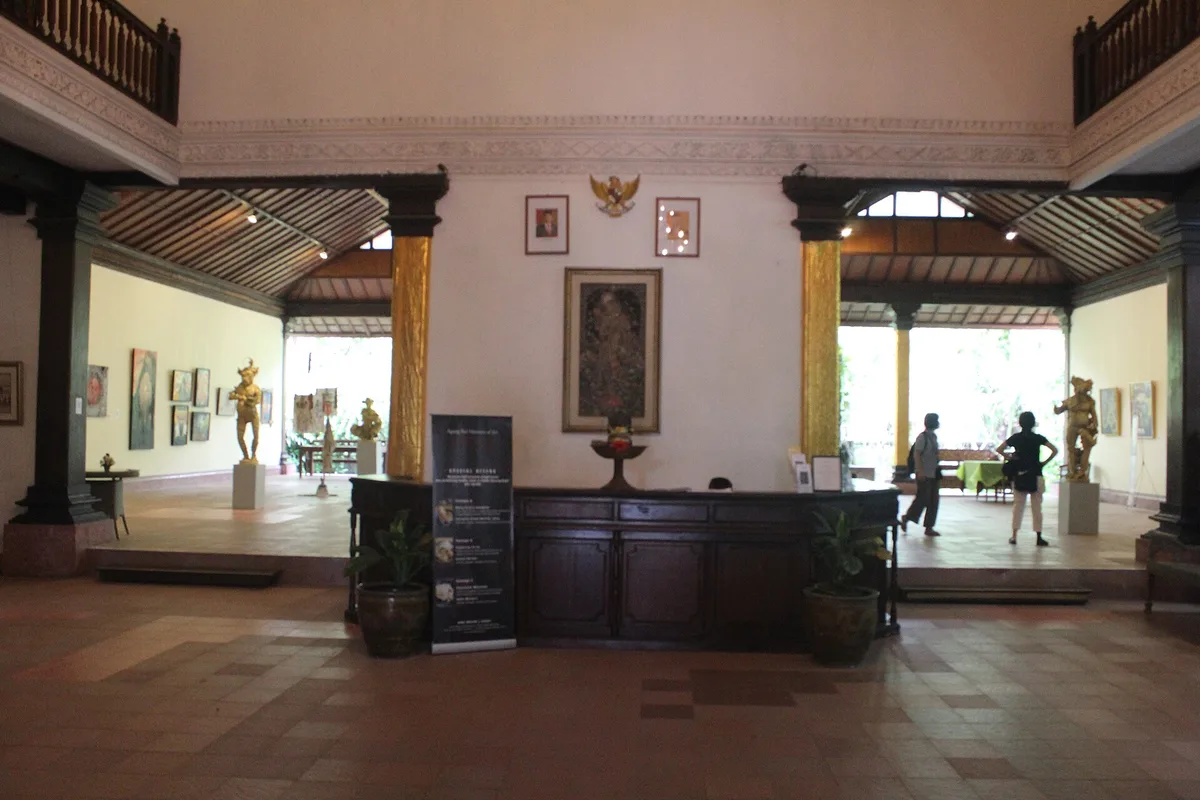 Ruang depan museum ARMA Ubud dengan meja resepsionis kayu panjang dan beberapa karya seni terpajang
