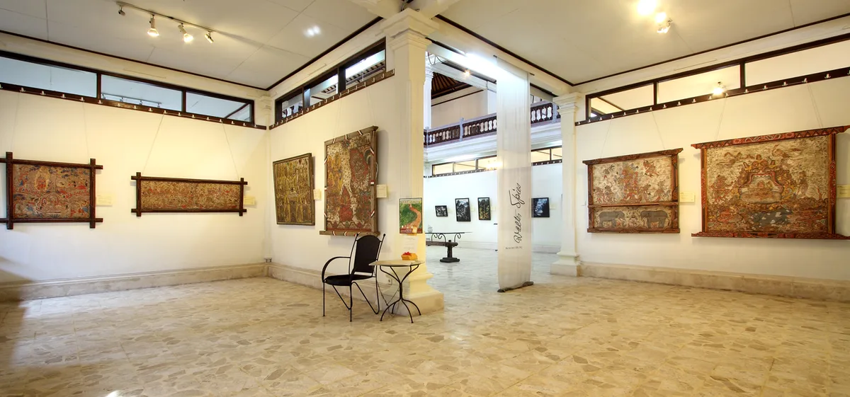 Ruang pameran ARMA Ubud dengan lukisan tradisional Bali berbingkai digantung berjajar di dinding putih