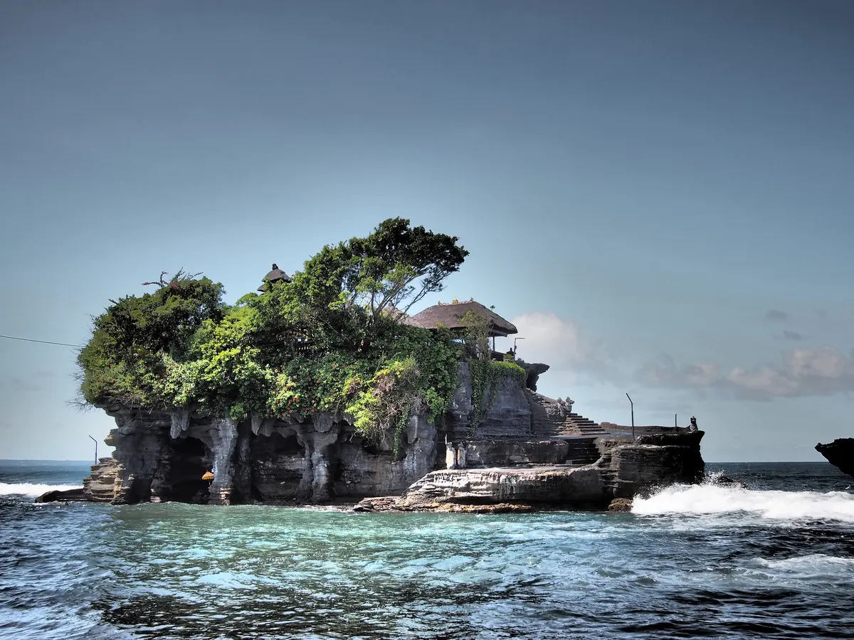 Pura Tanah Lot berdiri di atas karang laut dengan ombak pecah di kakinya