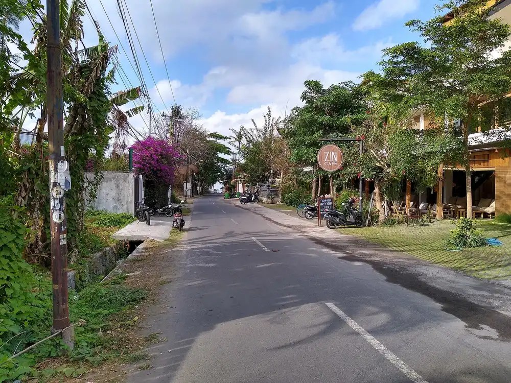 Jalan Nelayan di Canggu dengan deretan kafe di sisi kanan dan jalan aspal sempit dua arah