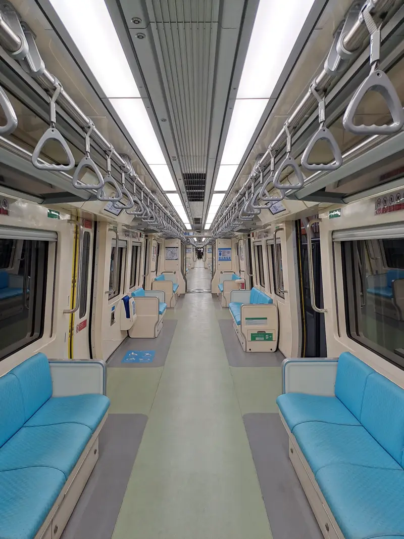 Interior LRT Jabodebek dengan kursi dan pegangan berdiri di sepanjang gerbong