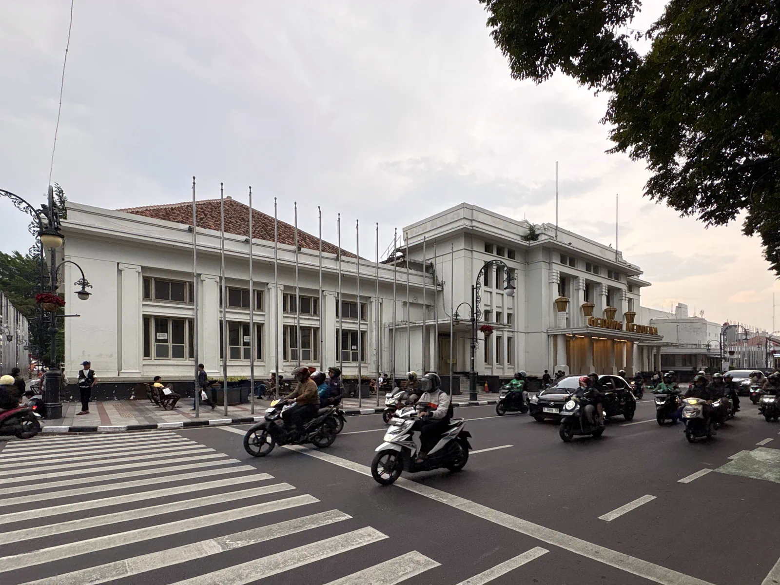 Gedung Merdeka bercat putih di tepi Jalan Asia Afrika Bandung dengan sepeda motor dan mobil melintas di depannya