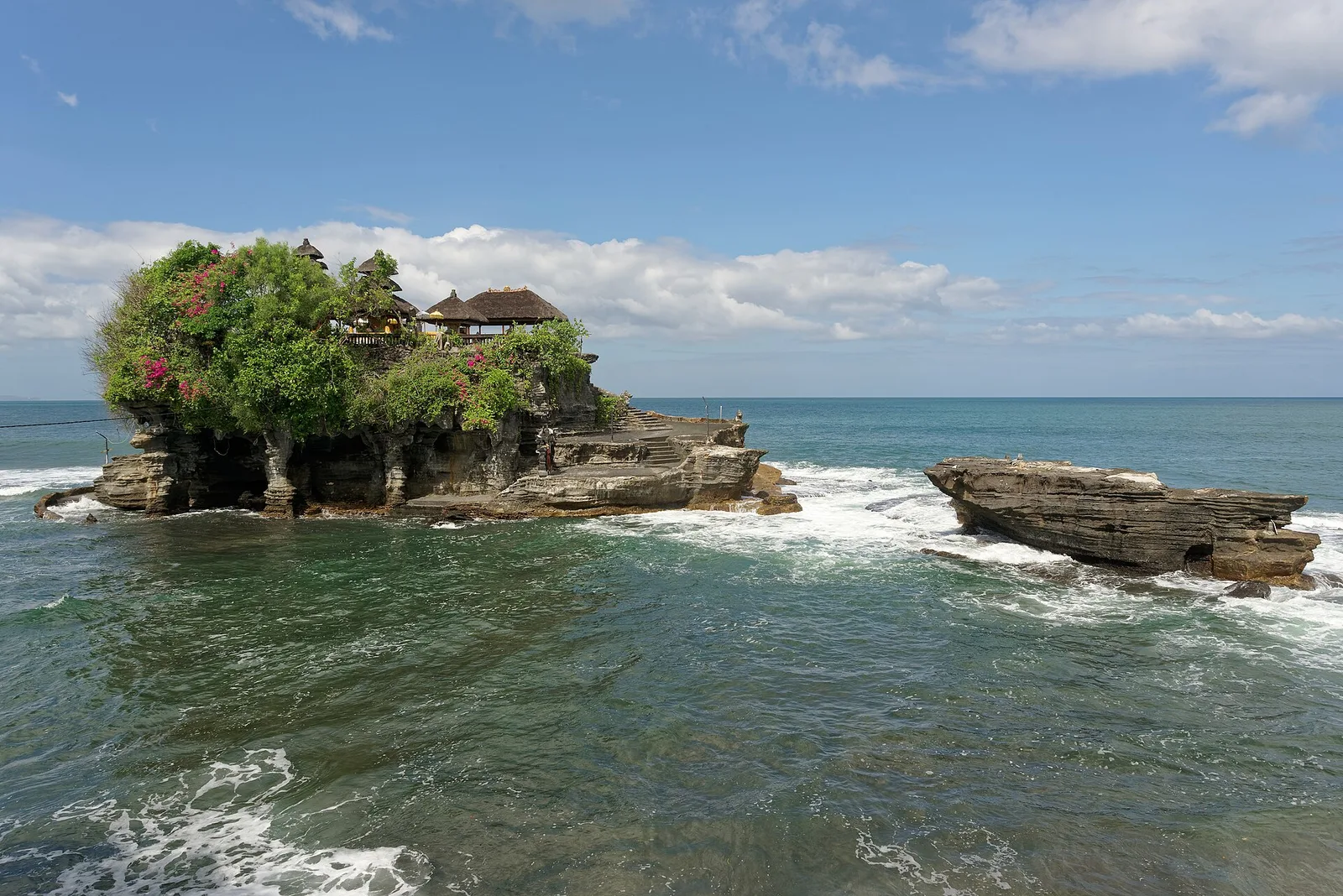 Pura Tanah Lot berdiri di atas bongkahan karang yang dikelilingi air laut saat pasang