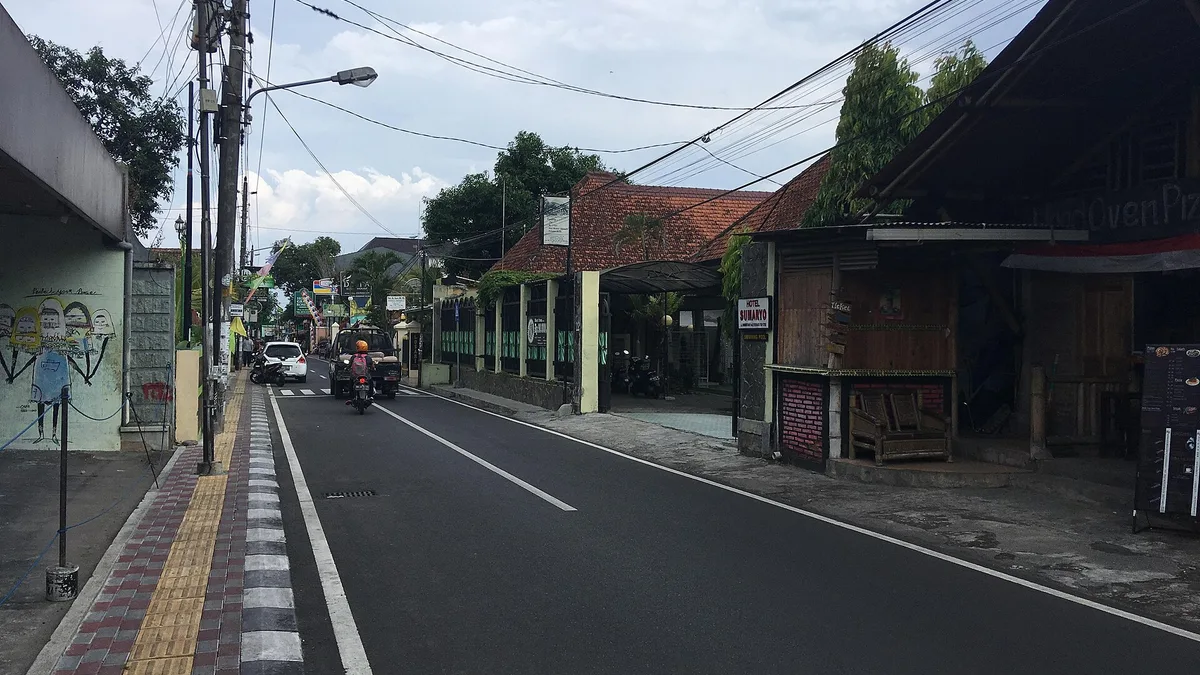 Jalan Prawirotaman di Yogyakarta dengan deretan bangunan beratap genteng, kafe, dan pengendara motor