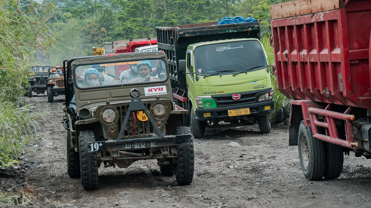 Jeep wisata berpenumpang berpapasan dengan truk pasir di jalan berbatu kawasan Kaliurang, Sleman