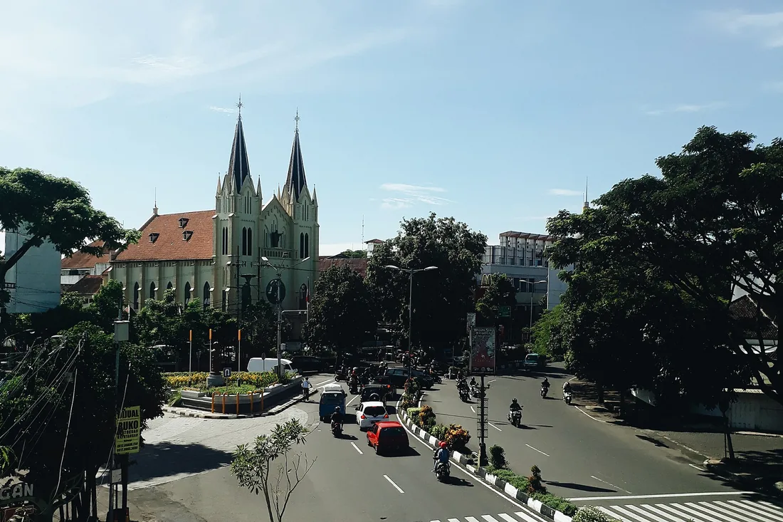 Jalan Kayutangan di pusat Kota Malang dengan menara kembar Gereja Hati Kudus Yesus dan lalu lintas motor