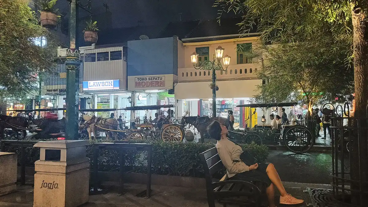 Suasana Jalan Malioboro pada malam hari dengan deretan andong menunggu penumpang dan pertokoan yang masih menyala