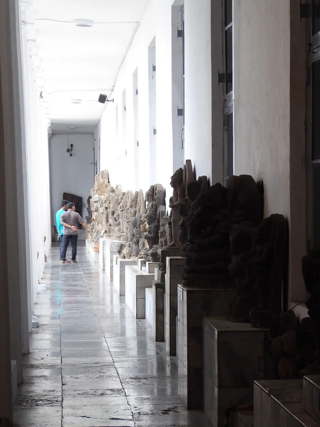 Deretan arca batu di atas alas beton berjajar sepanjang lorong galeri Museum Nasional Indonesia