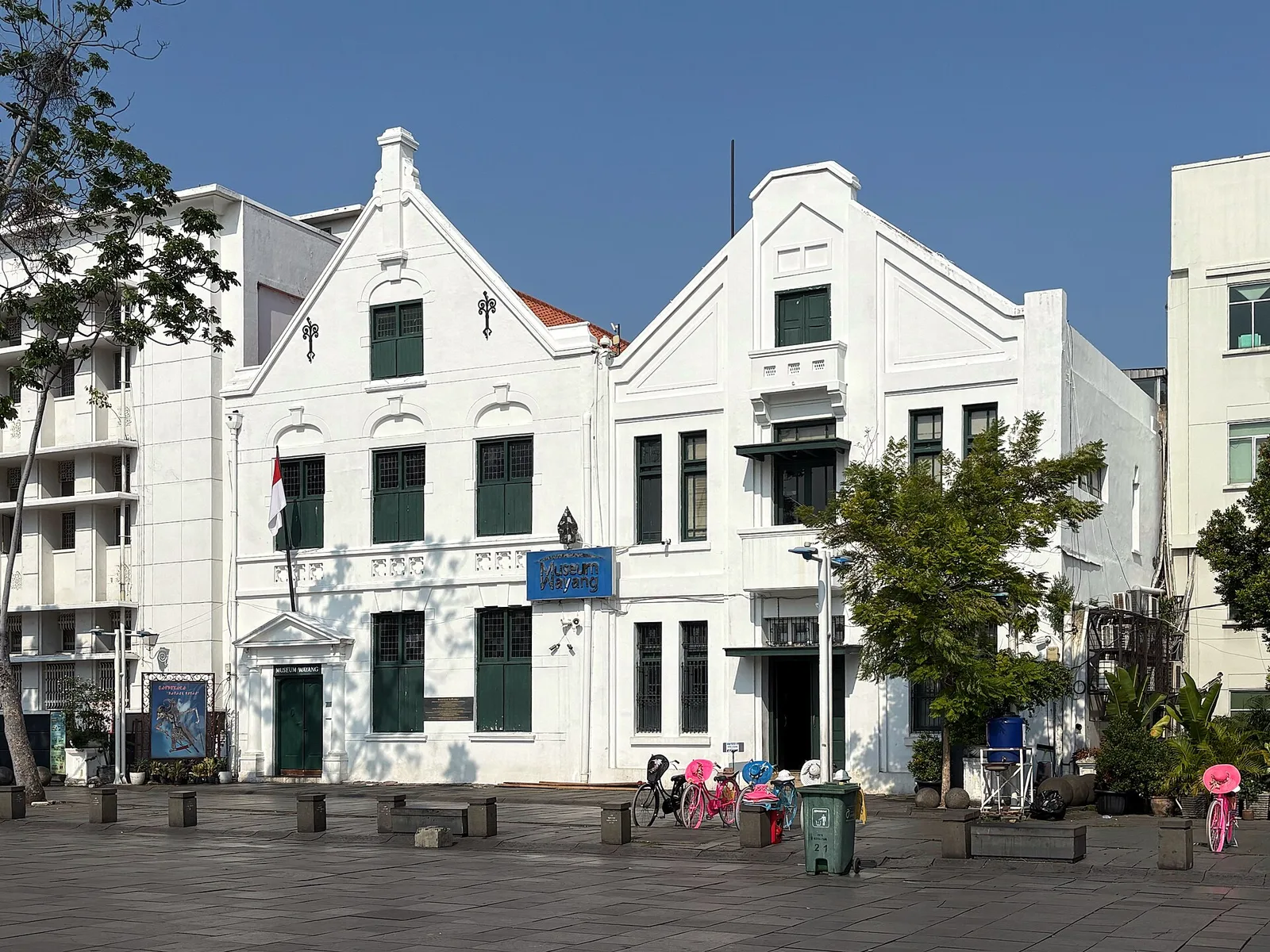 Fasad putih bergaya kolonial Belanda dengan atap pelana bertingkat, gedung Museum Wayang di tepi Taman Fatahillah, Kota Tua Jakarta