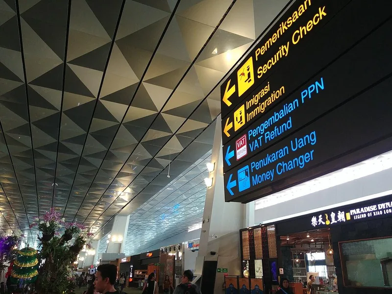 Papan petunjuk arah dwibahasa ke pemeriksaan keamanan, imigrasi, pengembalian PPN, dan penukaran uang di Terminal 3 Bandara Soekarno-Hatta
