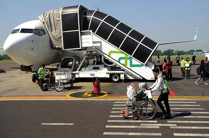Petugas mendorong penumpang lansia berkursi roda menuju pesawat di apron Bandara Adisutjipto Yogyakarta