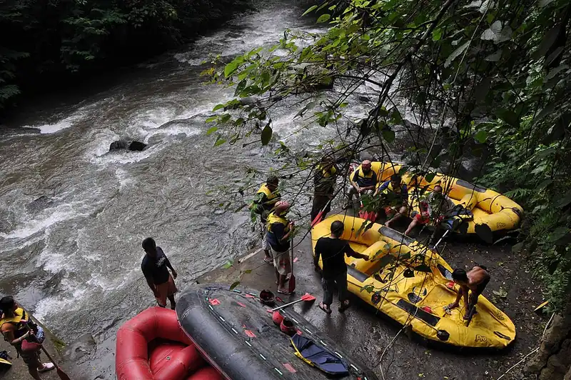 Peserta berjaket pelampung bersiap di samping perahu karet di titik start arung jeram Sungai Ayung, Bali
