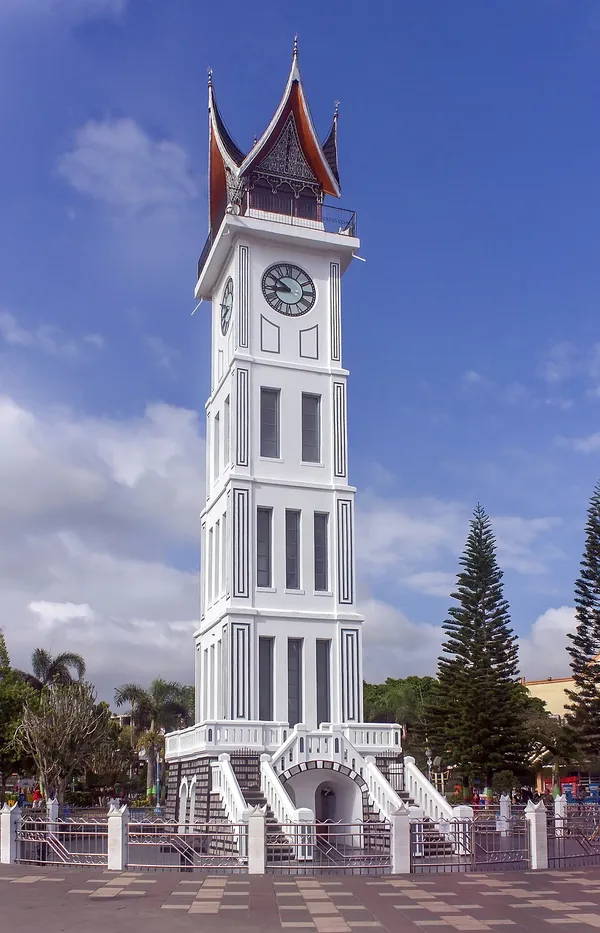 Menara Jam Gadang putih beratap gonjong khas Minangkabau di bawah langit biru