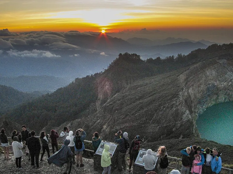 Wisatawan berjaket menyaksikan matahari terbit dari titik pandang puncak Kelimutu