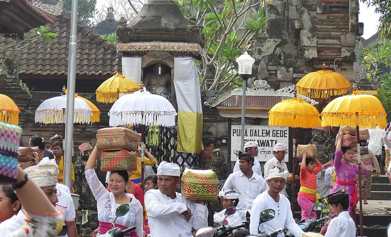 Umat Hindu berbusana adat Bali putih dan berkain membawa sesajen di depan Pura Dalem Gede Sukawati saat Galungan