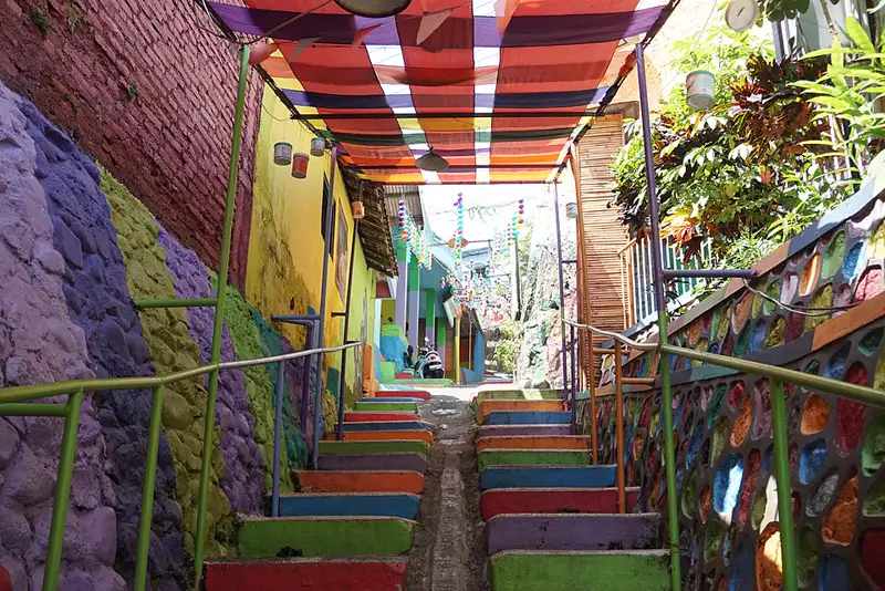 Anak tangga dicat warna-warni di gang Kampung Warna-Warni Jodipan dengan dinding bermotif dan atap kanopi berwarna