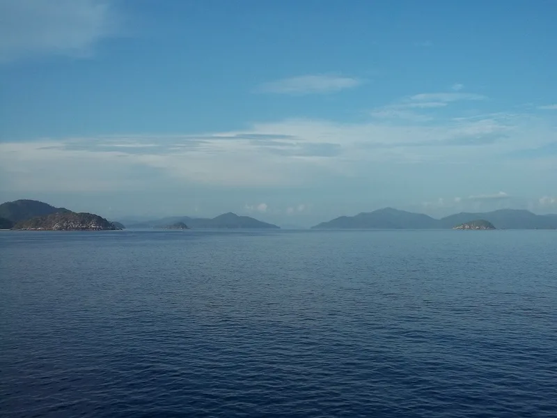 Deretan pulau berbukit di kejauhan di atas laut biru yang tenang, Kepulauan Anambas