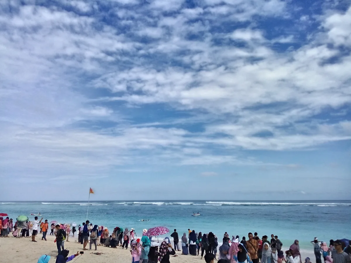 Pengunjung memenuhi bibir Pantai Pandawa, Bali, dengan air toska dan langit berawan