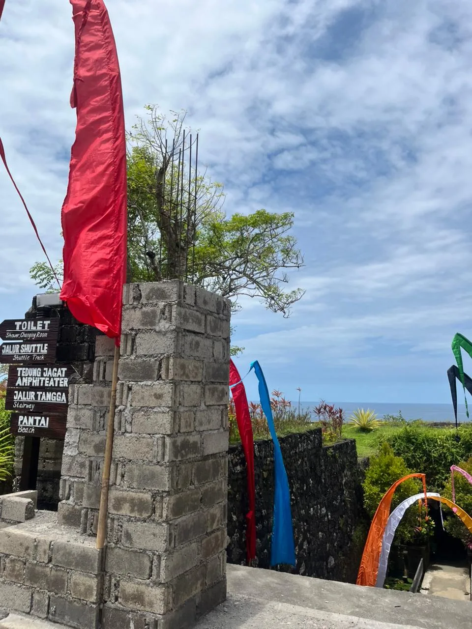 Papan penunjuk arah bertuliskan toilet, jalur shuttle, Tedung Jagat Amphiteater, jalur tangga, dan pantai di kawasan Pantai Gunung Payung