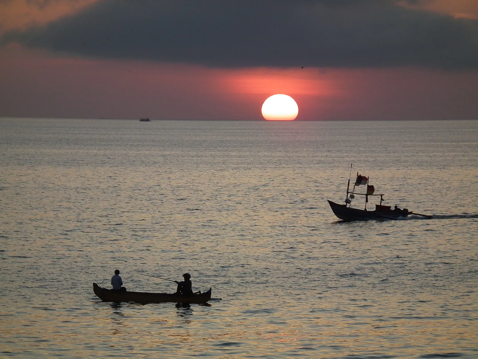 Siluet perahu nelayan melintas di depan matahari terbenam di Pantai Jimbaran