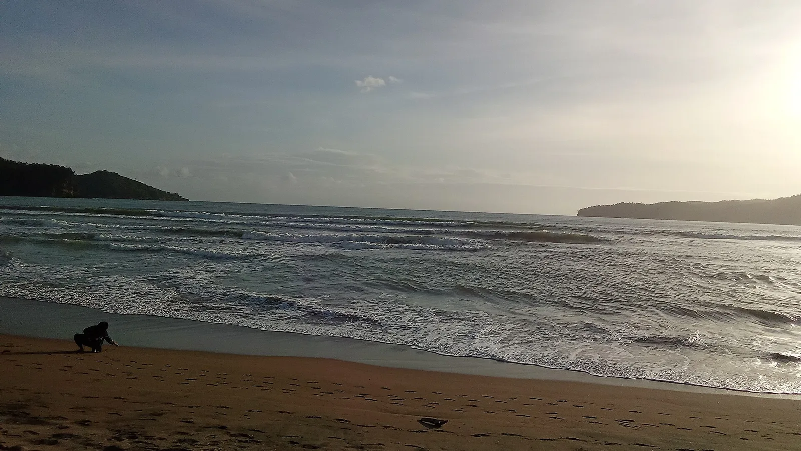 Teluk Pacitan dilihat dari Pantai Pancer Dorr dengan ombak berlapis dan bukit di kedua ujung teluk