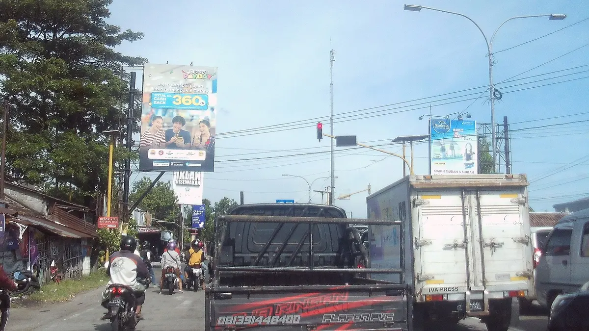 Simpang Jalan Lingkar Yogyakarta dengan truk boks, mobil bak, dan pengendara motor berhenti di lampu merah