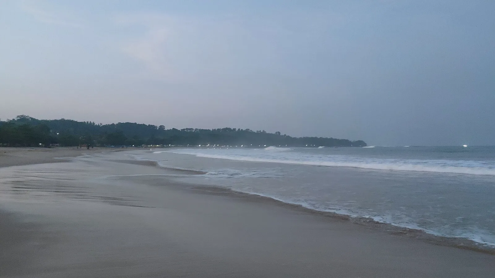 Hamparan pasir Pantai Ciantir di Sawarna menjelang gelap dengan deretan lampu di garis pepohonan