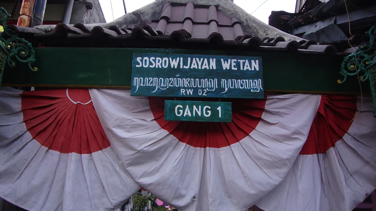Gapura bertuliskan Sosrowijayan Wetan Gang 1 dengan hiasan kain merah putih di gang dekat Malioboro