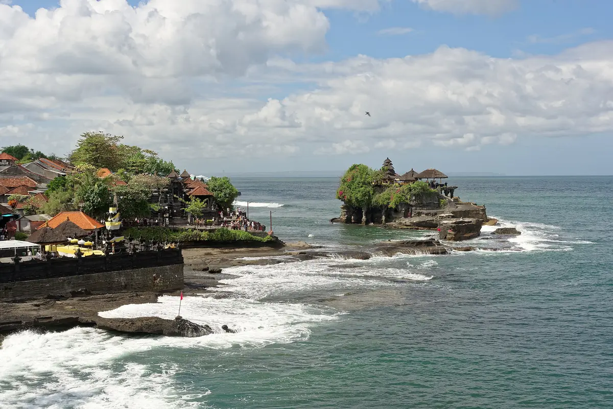 Kawasan Pura Tanah Lot saat air laut pasang, ombak menutupi jalur berbatu di bawah pura