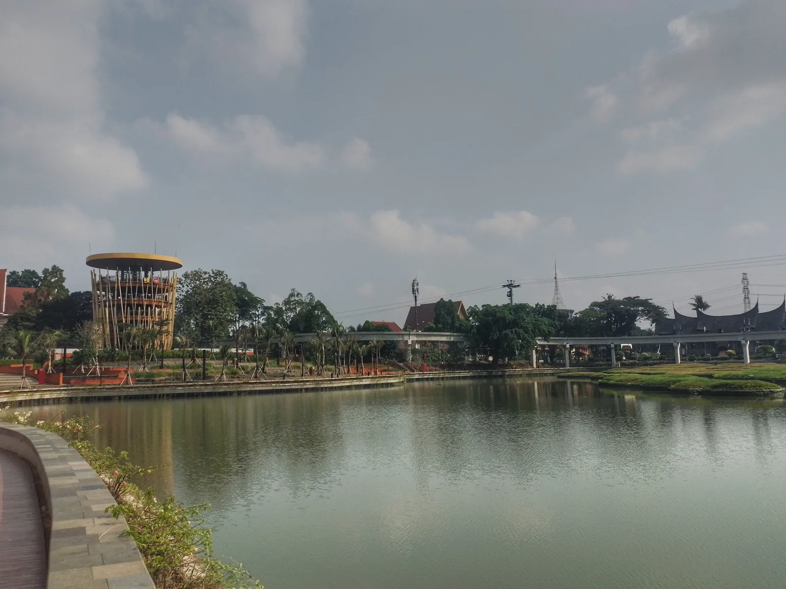 Danau Archipelago di Taman Mini Indonesia Indah dengan menara pandang di tepi kiri dan anjungan beratap gonjong Minangkabau di kejauhan