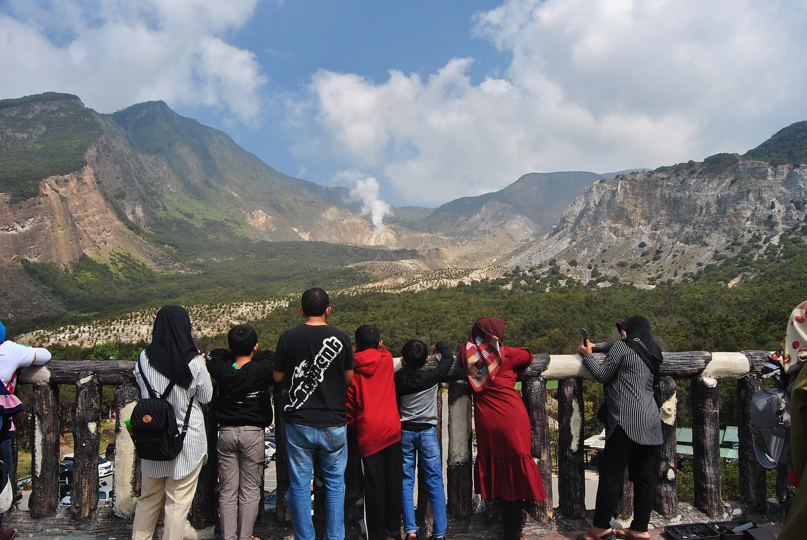 Pengunjung berdiri di pagar gardu pandang menghadap kawah Gunung Papandayan di Garut, dengan asap belerang mengepul dari dasar kawah