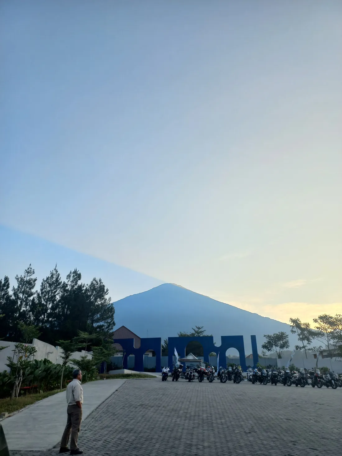 Gunung Ciremai terlihat dari kawasan Linggajati dengan gerbang bercat biru dan deretan sepeda motor di halaman depannya