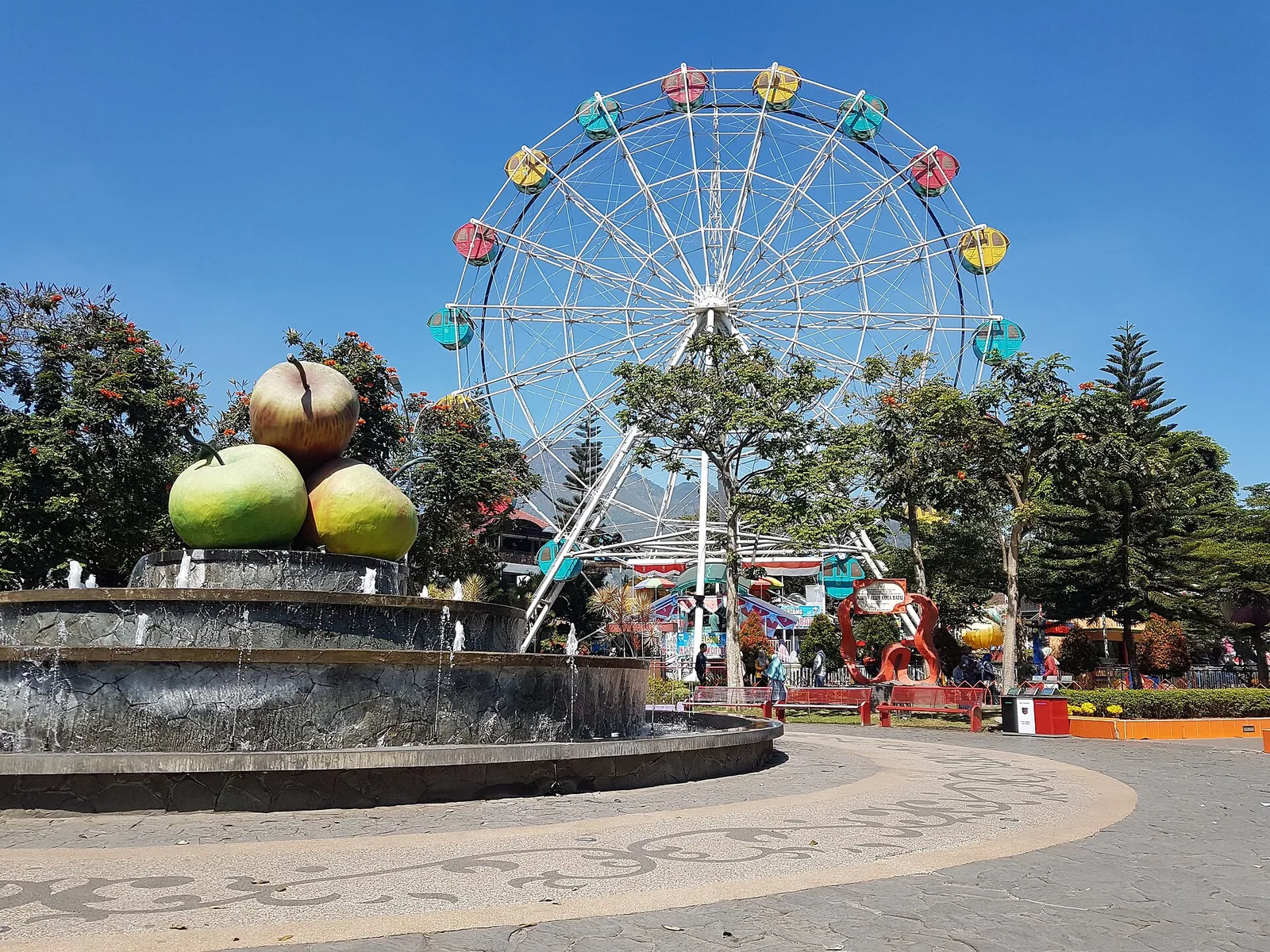 Air mancur berhias patung apel raksasa dengan bianglala berwarna-warni di belakangnya, Alun-Alun Kota Batu, Jawa Timur