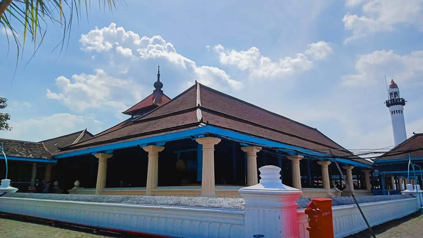 Masjid Agung Surakarta dengan atap tajug bertingkat dari sirap kayu, tiang-tiang serambi, dan menara putih menjulang di sisi kanan